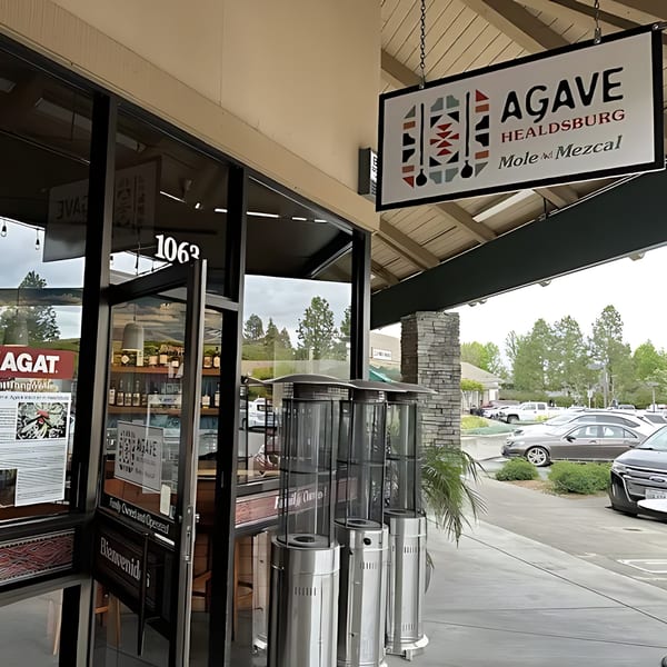 Exterior of Agave Mexican Restaurant with its sign, glass entrance, and outdoor heaters.