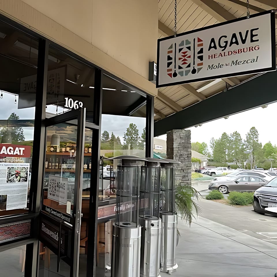 Exterior of Agave Mexican Restaurant with its sign, glass entrance, and outdoor heaters.